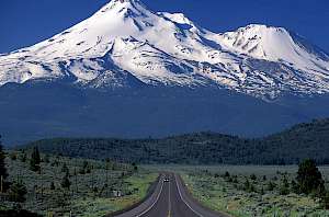 view of snow covered mount shasta with long road in the foreground